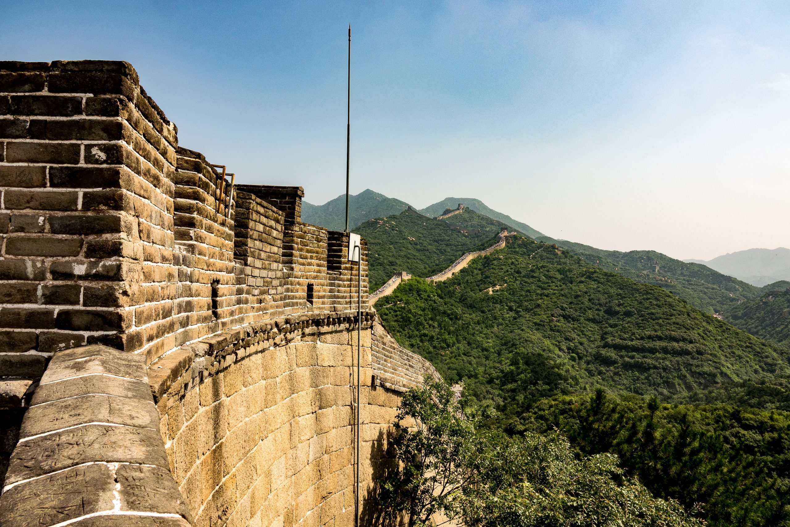 A high angle closeup shot of the famous Great Wall of China surrounded by green trees in summer